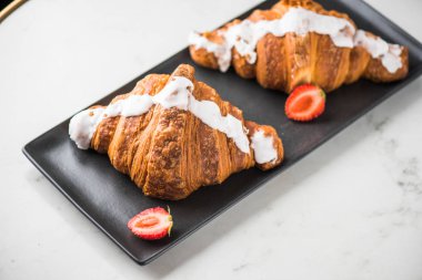 taze kruvasanlar siyah tabakta çilek ile