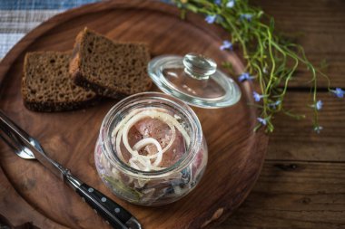 Soğan ekmek dilimleri ile ahşap tepsi üzerinde cam kavanoza salamura balık