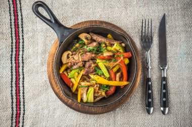 Keten kumaş üzerinde rustik tencerede et ile kavrulmuş karışık sebze