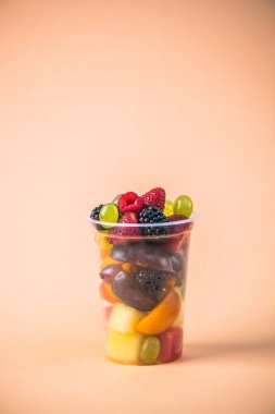 Taze meyve ve çilek bej renkli arka plan üzerinde plastik kap içinde