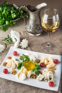 Beyaz şarap bir bardak gri masa örtüsü üzerinde peynir tabağı