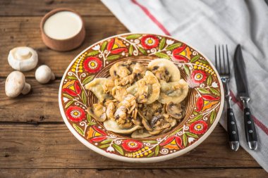 Ahşap masa üzerinde rustik çiçek desenli plaka üzerinde kızarmış yağlı mantar ile ev yapımı köfte