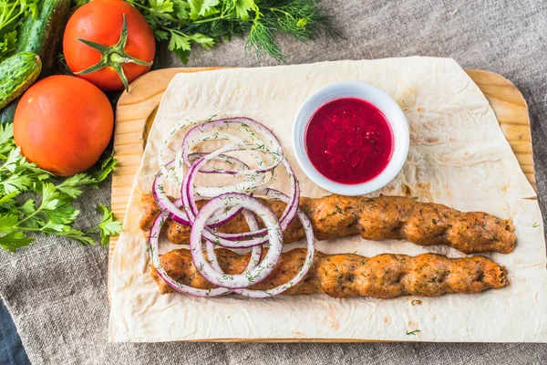 Soğan ve düz ekmek ile ahşap tahta üzerinde ızgara kebaplar