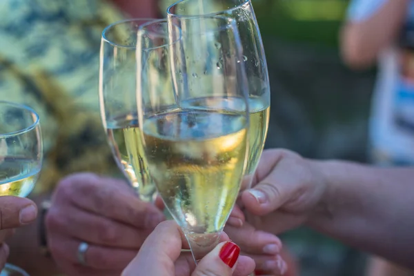 close-up of people clinking champagne glasses outdoors