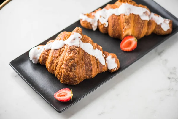 taze kruvasanlar siyah tabakta çilek ile