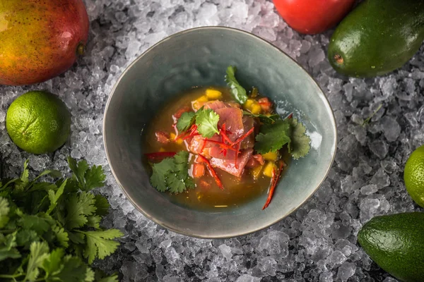 Seafood snack with vegetables in bowl on ice with ingredients