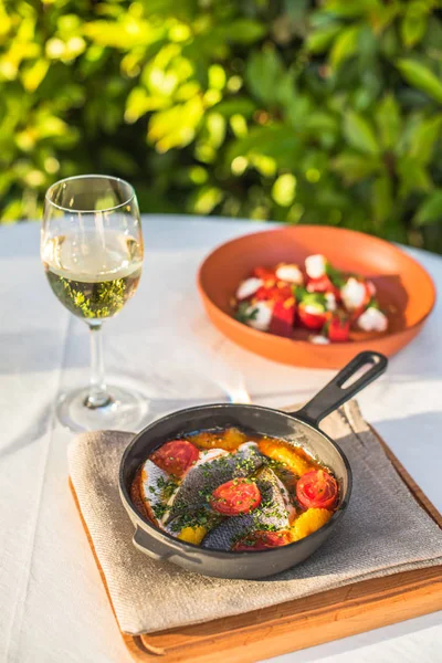 Makarna salatası ve beyaz şarap ile Bahçe tabloda tavada kızarmış balık