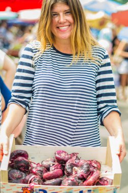 Çiftçi pazarında taze soğanları tutarak gülümseyen genç kadın