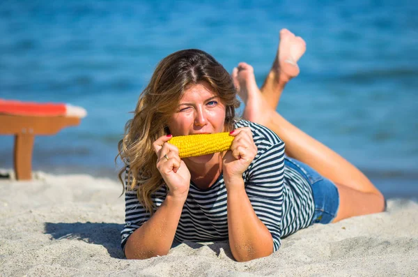 Mulher Positiva Deitada Praia Areia Comendo Espiga Milho — Fotografia de Stock