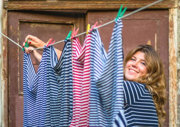 Genç kadın kırsal evin önünde ip açık havada çamaşır asılı