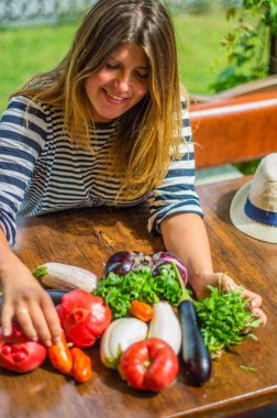 taze sebze yığını ile oturan gülümseyen kadın