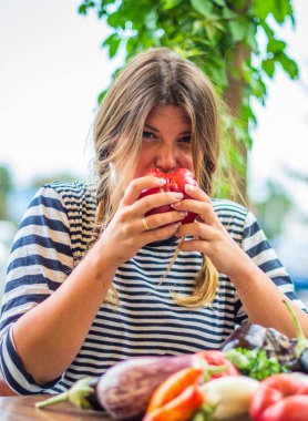 Sevimli kadın masada çiğ sebze ile bütün taze kırmızı domates yeme
