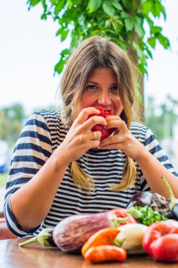 Sevimli kadın masada çiğ sebze ile bütün taze kırmızı domates yeme