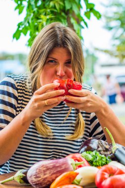 Sevimli kadın masada çiğ sebze ile bütün taze kırmızı domates yeme