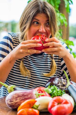 Sevimli kadın masada çiğ sebze ile bütün taze kırmızı domates yeme