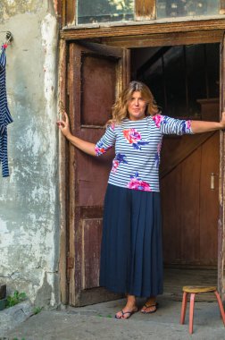 Kırsal kesimde eski püskü rustik evin kapı çerçeve içinde duran pozitif kadın