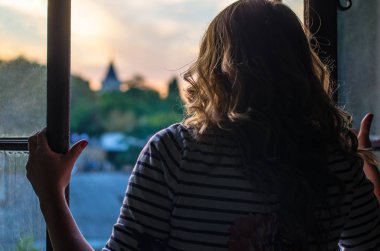 gün batımında eski çatılar ve şehir manzaralı pencere açan kadının yakın çekim