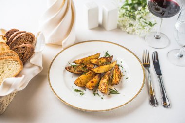 Restoranda beyaz masada plaka üzerinde servis edilen kavrulmuş patates takozları