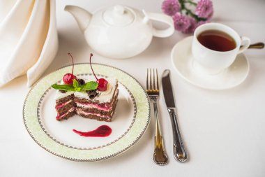 kiraz plaka, çiçekler ve tabloda çay ile lezzetli tatlı pasta