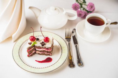 kiraz plaka, çiçekler ve tabloda çay ile lezzetli tatlı pasta