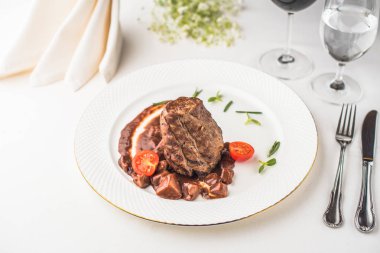 lezzetli biftek domates tabak, çatal bıçak ile ve gözlük ile şarap ve su Restoran masada