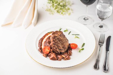 lezzetli biftek domates tabak, çatal bıçak ile ve gözlük ile şarap ve su Restoran masada