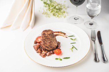 lezzetli biftek domates tabak, çatal bıçak ile ve gözlük ile şarap ve su Restoran masada