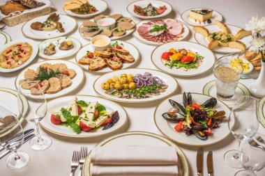 Birçok farklı yemek restoran tablo. Tabak, çatal, bıçak, beyaz masa örtüsü gözlük. Vazoda Çiçekler