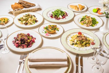 Çok lezzetli yemekleri ile restoran tablo. Tabak, çatal, bıçak, beyaz masa örtüsü gözlük. Vazoda Çiçekler