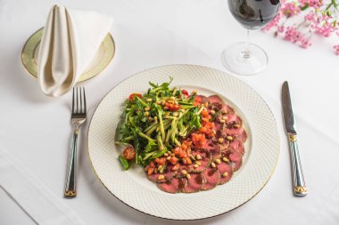 tabak, çatal bıçak, bir bardak şarap ile sebze ve Restoran masaya çiçek ile gurme et yemek