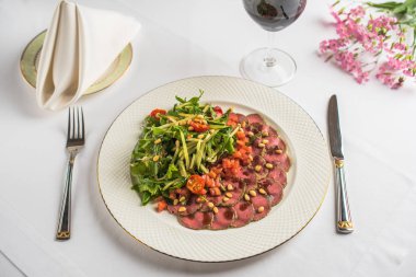 tabak, çatal bıçak, bir bardak şarap ile sebze ve Restoran masaya çiçek ile gurme et yemek