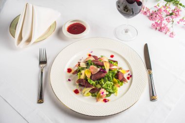 parma jambon ve yenilebilir çiçekler ile plaka, sos, kadeh şarap ve çatal bıçak Restoran tablo ile lezzetli yemek