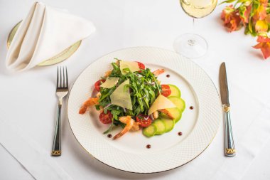 Karides ve masada beyaz tabakta peynirli taze sebze salatası