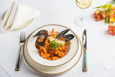 Deniz ürünleri, midye ve kalamar tabak, bardak şarap ve Restoran masaya çiçek ile gurme yemek