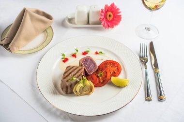 Beyaz tabak, çatal bıçak ve pembe gerbera çiçek Restoran tablo ile domates gurme etli