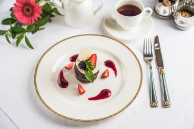 Çilek ile dekore edilmiş ve tepesi çikolata tatlı kahve ile beyaz tabakta servis