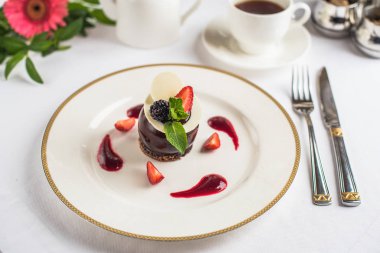Çilek ile dekore edilmiş ve tepesi çikolata tatlı kahve ile beyaz tabakta servis