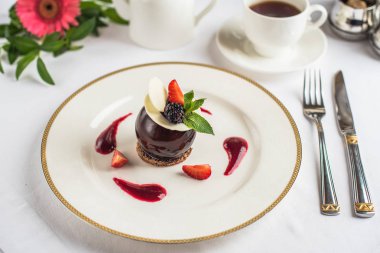 Çilek ile dekore edilmiş ve tepesi çikolata tatlı kahve ile beyaz tabakta servis