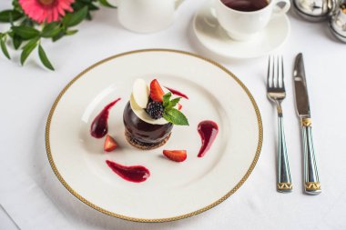 Çilek ile dekore edilmiş ve tepesi çikolata tatlı kahve ile beyaz tabakta servis