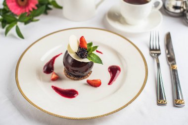 Çilek ile dekore edilmiş ve tepesi çikolata tatlı kahve ile beyaz tabakta servis