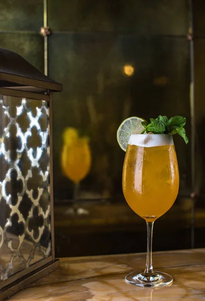 Drink in glass with ice, lemon and mint leaves. Cocktail close-up on restaurant table.