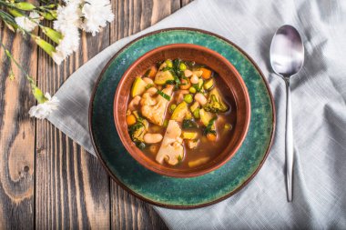 Ahşap masa ıslak zeminde çiçeklerle servis ev yapımı sebze çorbası