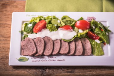 Dilimlenmiş et, salata yaprakları ve tabakta domates ile snack