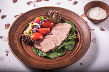 Dilimlenmiş et, salata yaprakları ve tabakta domates ile snack