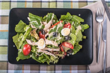 Yumurta ve zeytin siyah damalı masa örtüsü tepside üzerinde taze salata