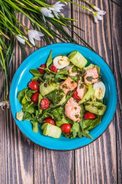 Taze sebze salatası somon ve çiçekler ile ahşap masa üzerinde bir kapta yumurta