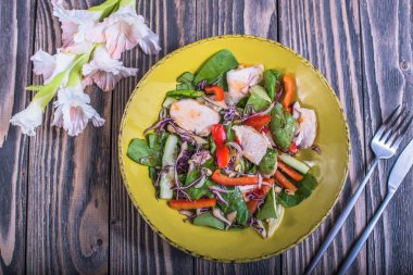 Sarı çiçekli ahşap masa tabakta tavuk ile taze sebze salatası