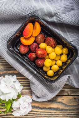 Taze meyve ve çilek ahşap masa üzerinde plastik kap içinde