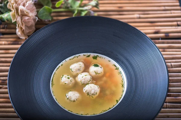 homemade soup with meat balls served in black plate on bamboo napkin