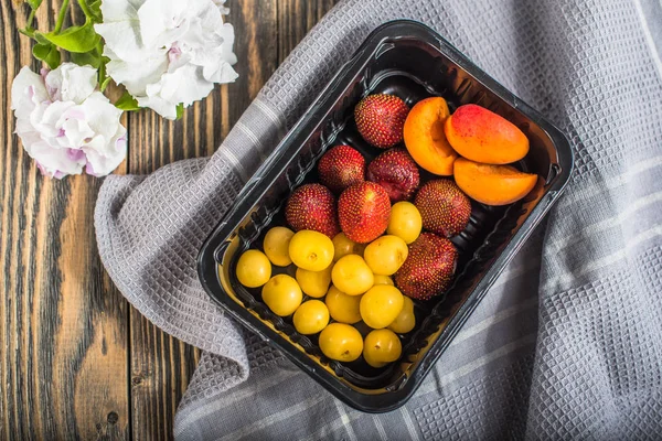 Taze meyve ve çilek ahşap masa üzerinde plastik kap içinde